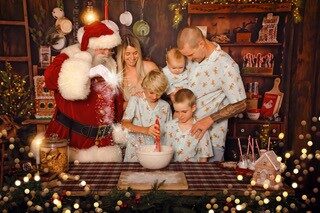 Santa baking gingerbread with a family in a cosy cabin