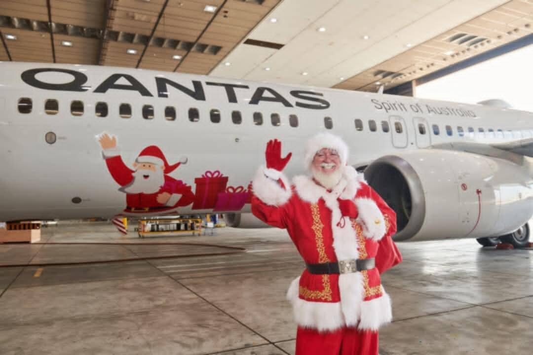 Santa Steve waving in front of a Qantas plane