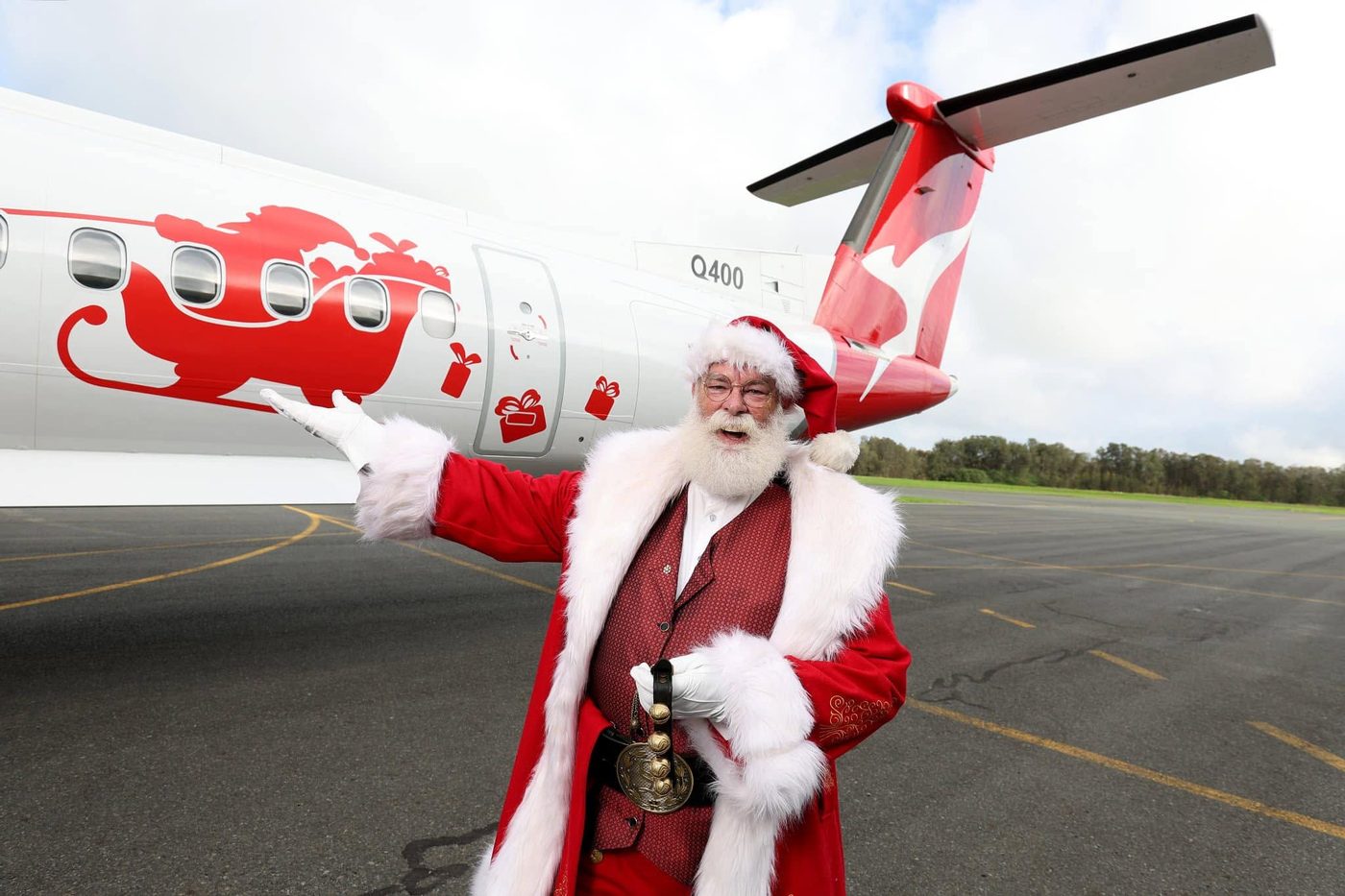 Santa waving beside a festive plane
