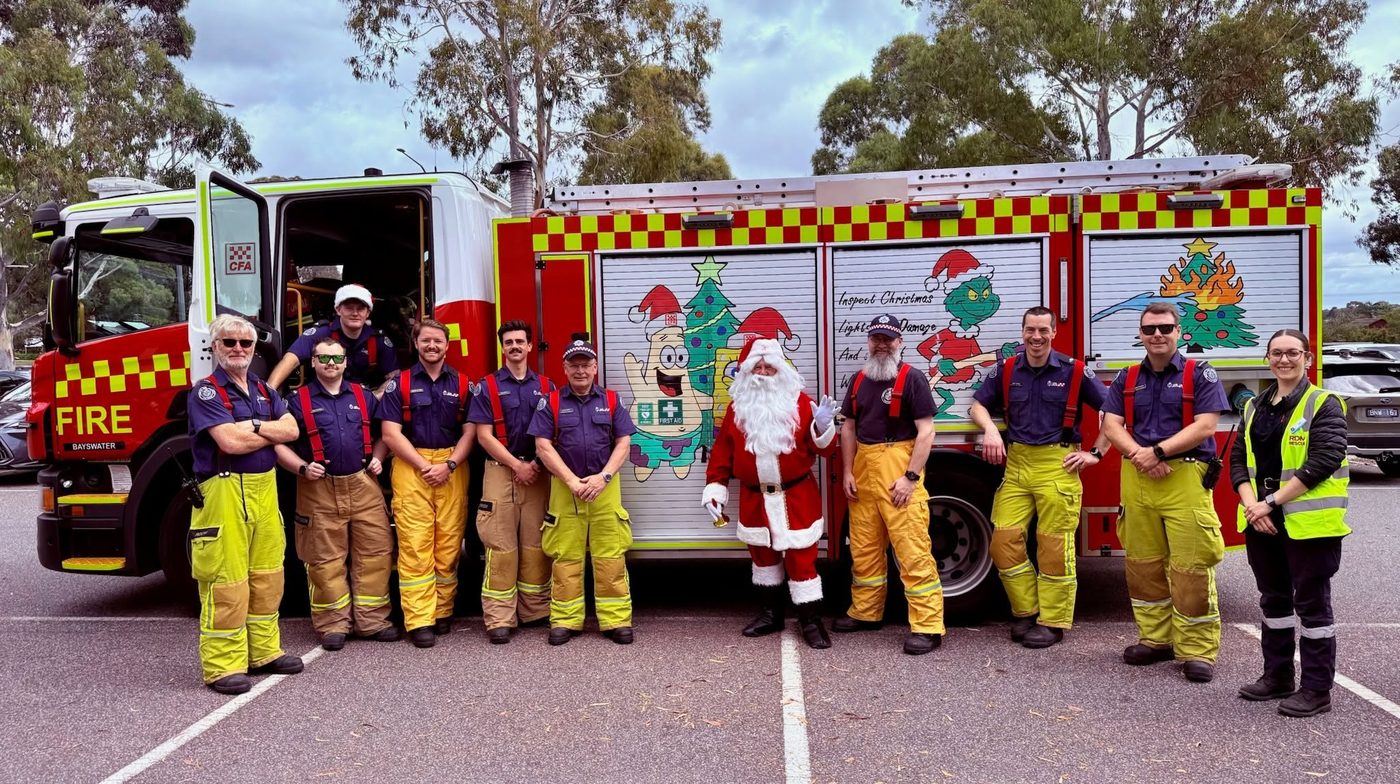 Santa with a team of firefighters in front of a fire truck